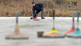 Ein Eisstocksch&uuml;tze geht auf einem zugefrorenen Weiher seinem Hobby nach.