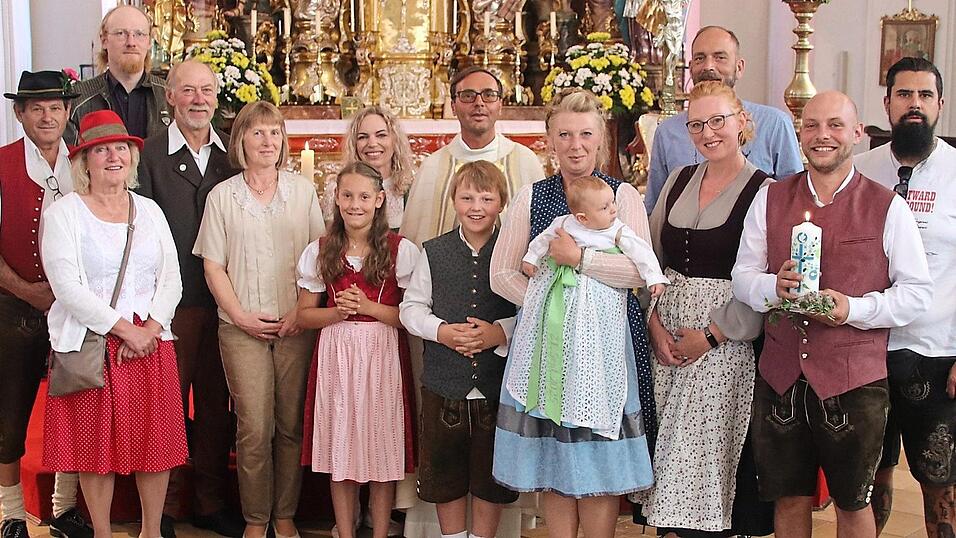 Sedrik Weber auf dem Arm seiner Patin Susanne Ruhland, flankiert von seinen Eltern und der &uuml;brigen Taufgesellschaft mit Pfarrer Dr. Augustinus Kozdra.