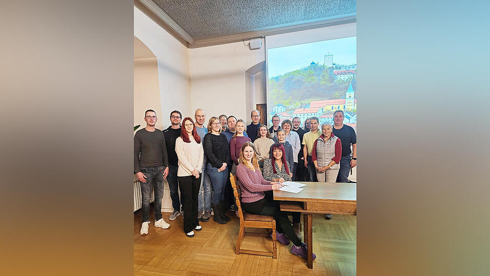 Regisseurin Melody Bayer (sitzend, vorne) mit Bürgermeisterin Heike Fries bei der Vertragsunterzeichnung. Dahinter die Burghofspieler mit altbekannten und neuen Gesichtern sowie einer der Koordinatoren, Karl Semmelmann, und Angela Wilholm vom Tourismusbüro.