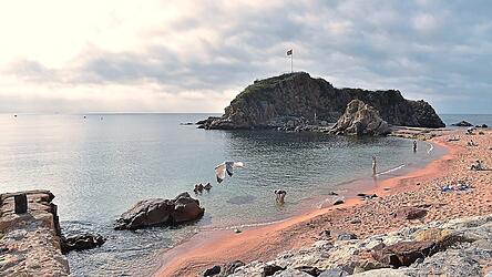 Morgens ist der Strand von Blanes meist noch leer. Die Felsengruppe Sa Palomera, die hier das Mittelmeer umsp&uuml;lt, gilt als Tor zur Costa Brava, der &bdquo;Wilden K&uuml;ste&ldquo;. Am Ostrand Kataloniens erstreckt sie sich fast bis nach Frankreich.