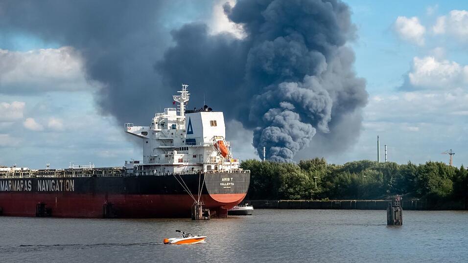 Rauch ist hinter einem Schiff zu sehen; in der Nähe des Einsatzortes fließt die Norderelbe.