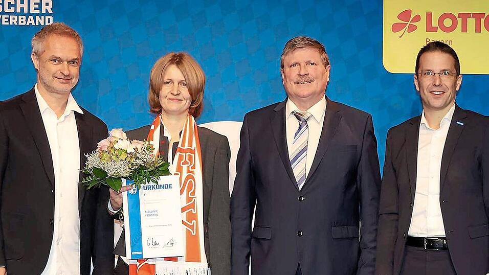 Mit FSV-Schal auf der großen Bühne: BFV-Präsident Christoph Kern (r.) und Frauen-Bundestrainer Christian Wück (l.) überreichten mit Ehrenamtsbeauftragten Rudolf Hamberger Melanie Fröschl die Urkunde zum Ehrenamtspreis des Bayerischen Fußbalverbandes.