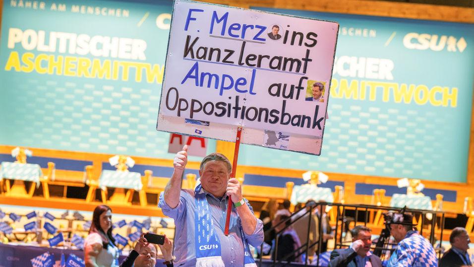 Ein CSU-Anh&auml;nger h&auml;lt beim Politischen Aschermittwoch der CSU ein Schild mit der Aufschrift 'F. Merz ins Kanzleramt - Ampel auf die Oppositionsbank in die H&ouml;he.