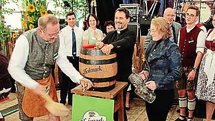 Assistiert vom Ehrenschirmherrn Dekan Ralf Heidenreich zapft Schirmherr Gerhard Kerscher das erste Fass Bier an.