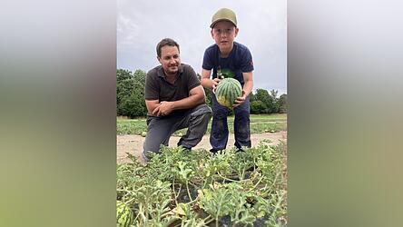 Max Faltermeier - links Papa Martin - zeigt eine reife Melone, die er gerade geerntet hat.
