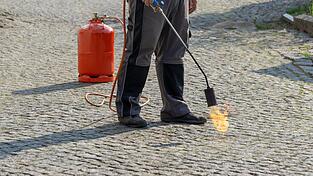 Mit einem Gasbrenner lassen sich Pflasterfugen mühelos von Unkraut befreien. Allerdings sind sie überdurchschnittlich oft für Heckenbrände verantwortlich.