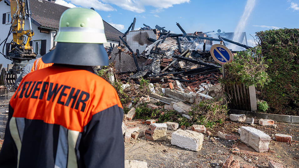 Ein Feuerwehrmann steht vor den Tr&uuml;mmern des Wohnhauses.