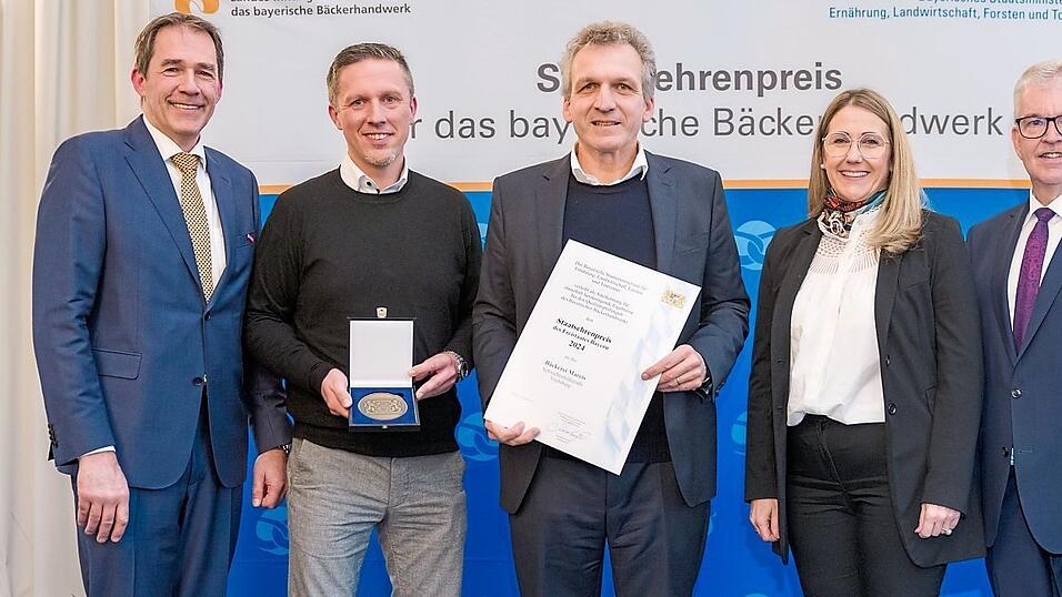Das Bild zeigt Gesch&auml;ftsf&uuml;hrer und Inhaber Anton Mareis (Mitte) mit Backstubenleiter Lukas Romanski (Zweiter von links) und B&uuml;rgermeisterin Sibylle Entwistle bei der Verleihung des Bayerischen Staatsehrenpreises f&uuml;r das B&auml;ckerhandwerk durch Landesinnungsmeister Heinrich Traublinger (links) und Amtschef Hubert Bittlmayer.