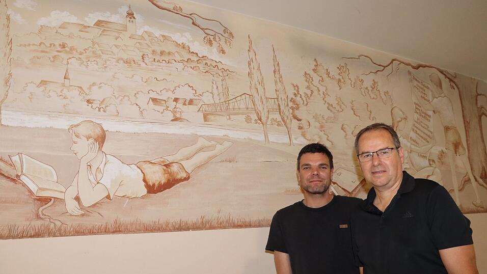 Schulleiter Alfred Reithmeier (r.) und Josef Plank von der erweiterten Schulleitung stehen vor einem Gemälde von Architekt Wilhelm Pfrogner aus dem Jahr 1953, das anlässlich des Neubaus der Schule am heutigen Standort entstand und noch immer den Schulflur ziert.