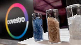 Eine deutsche Firma wird arabisch: Das Logo des Spezialchemie-Konzerns in einem Firmen-Showroom, davor Gläser mit Covestro-Materialien. Eine deutsche Firma wird arabisch: Das Logo des Spezialchemie-Konzerns in einem Firmen-Showroom, davor Gläser mit Covestro-Materialien.