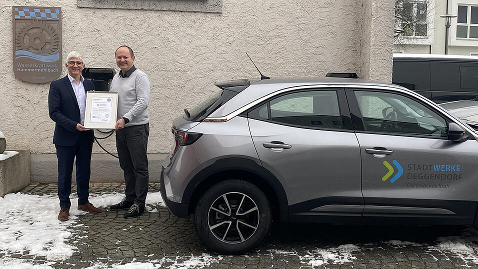 Stadtwerke-Gesch&auml;ftsf&uuml;hrer Alexander Springer (l.) pr&auml;sentiert gemeinsam mit dem Technischen Leiter und Leiter des Energieteams, Gerhard Kuchler (r.), das Zertifikat neben dem j&uuml;ngst angeschafften Elektroauto.