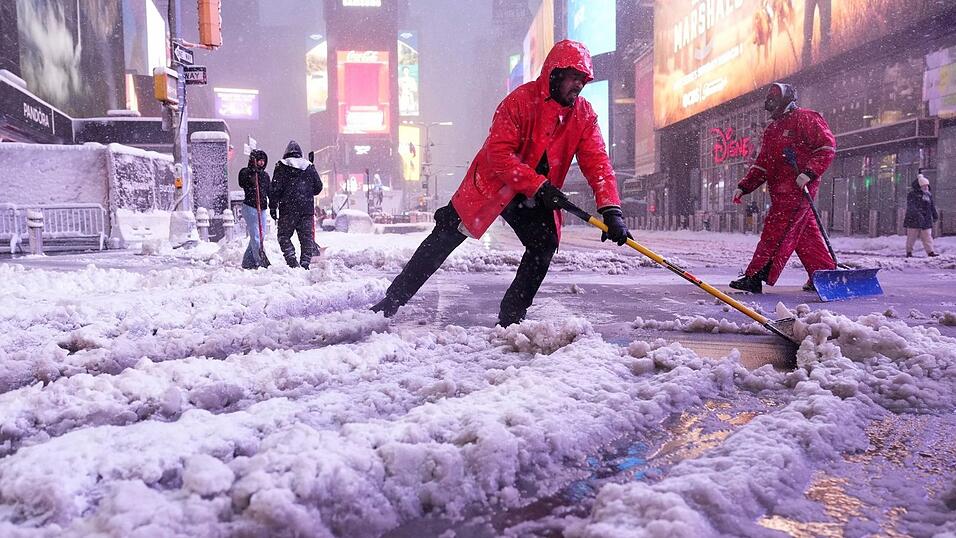 Ein Arbeiter schaufelt Schnee auf dem Times Square in New York. Ein heftiger Schneesturm zieht über den Nordosten der USA hinweg. Ein Arbeiter schaufelt Schnee auf dem Times Square in New York. Ein heftiger Schneesturm zieht über den Nordosten der USA hinweg.