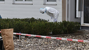 Ein Kriminaltechniker der Polizei schaut vor einem Haus, das ein Tatort ist, nach Spuren. Ein Kriminaltechniker der Polizei schaut vor einem Haus, das ein Tatort ist, nach Spuren.
