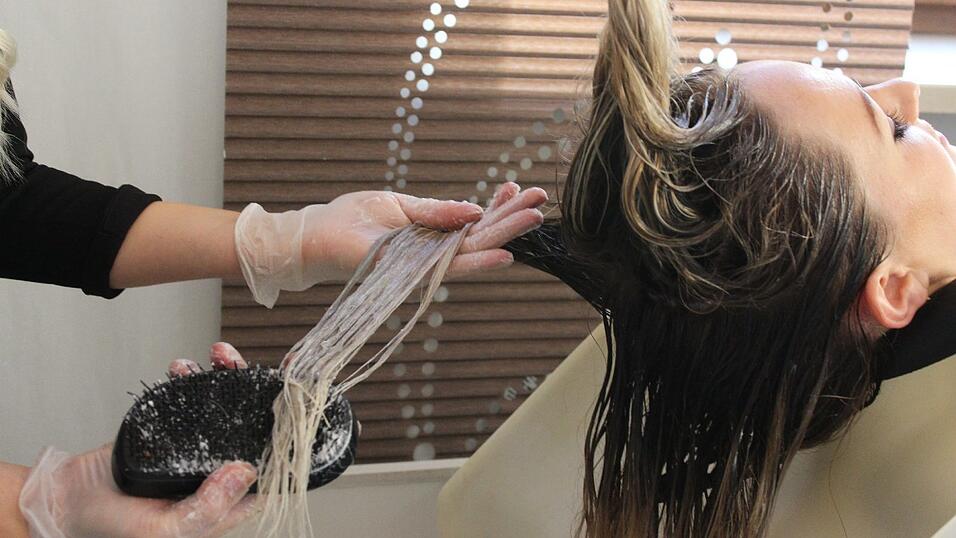 Hairstylistin Ola Els&auml;sser tr&auml;gt die Farbe auf und k&auml;mmt mit einem speziellen Kamm immer wieder durch.
