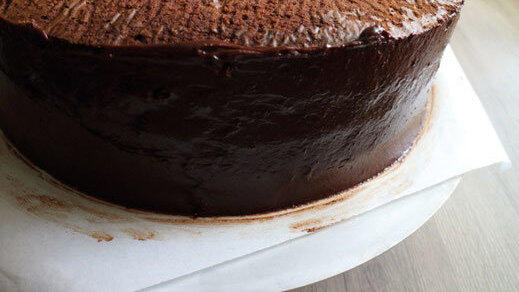 Die überschüssige Ganache von der Torte entfernen.