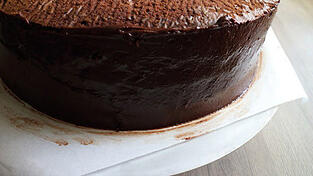 Die überschüssige Ganache von der Torte entfernen.