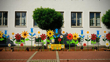 Das Titelblatt des Kalenders von Joachim Walter zeigt die heuer im Rahmen des Ferienprogramms aufgestellten farbenfrohen Holzblumen vor dem Rathaus.