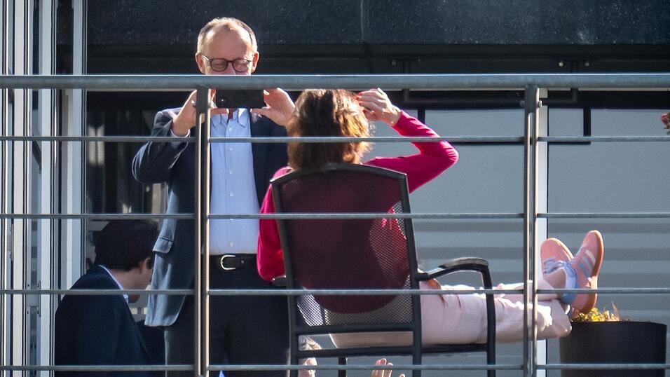 Doro Bär von der CSU wirft sich auf einer Terrasse des Jakob-Kaiser-Hauses in Positur, ihr lila Oberteil leuchtet wie eine Tulpe im hellen Licht. CDU-Chef Friedrich Merz zückt sein Handy und schießt ein Bild.