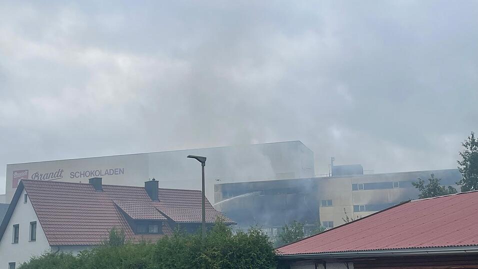 Auch um 12.10 Uhr sind noch starke Rauchschwaden am Gel&auml;nde zu sehen. Die Feuerwehr tut alles, um das Feuer zu l&ouml;schen.
