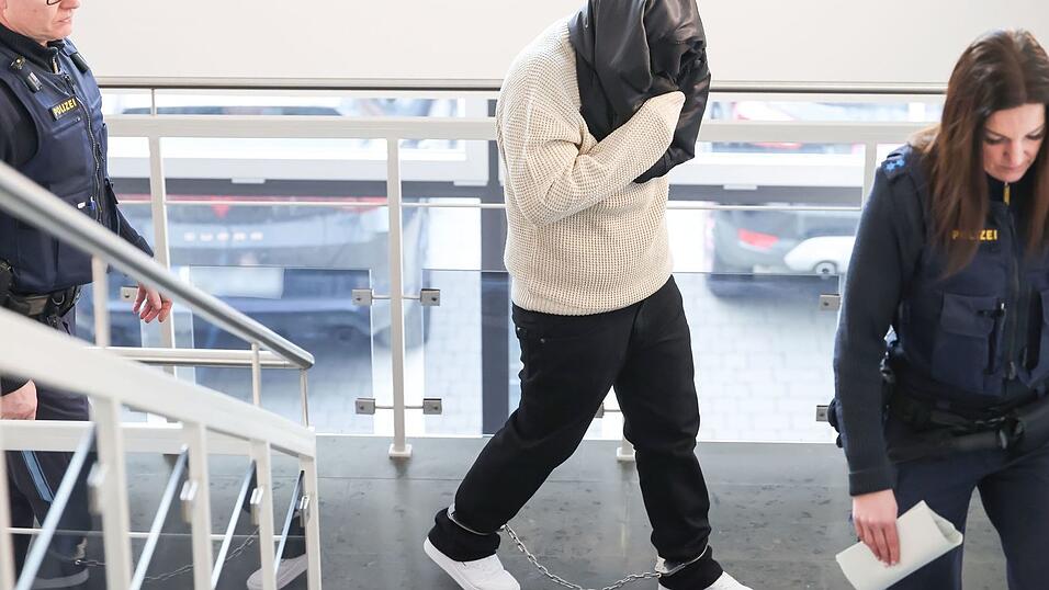 Die Angeklagte hat sich eine Jacke um den Kopf gewickelt, um ihr Gesicht vor den Kameras zu verbergen.