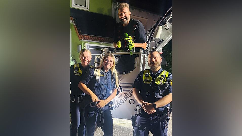 In sicheren Händen: Einsatzkräfte der Polizei mit Daniel Edlbauer von der Feuerwehr Lappersdorf. Er hält den grünen Papagei.