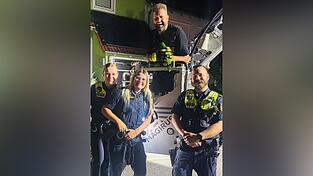 In sicheren Händen: Einsatzkräfte der Polizei mit Daniel Edlbauer von der Feuerwehr Lappersdorf. Er hält den grünen Papagei.