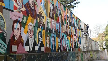 Oleg Kuzenko bei der Arbeit: 132 Regensburger Persönlichkeiten hat er auf der Mauer verewigt.