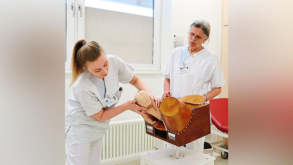 An einem &Uuml;bungsbecken &uuml;bt Giesen mit den Studentinnen,wie man als Hebamme bei einer Geburt agiert.