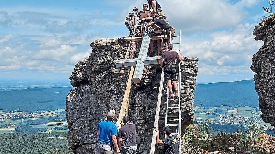 Die Helfer beim Hochheben des Kreuzes auf den Felsen.