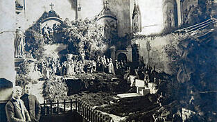 Michael Steinböck mit seinem Sohn Johann um 1930 vor seiner Krippe, aufgebaut in der damaligen Seitenkapelle der Pfarrkirche St. Martinus. Dargestellt ist die Auferstehung Christi.