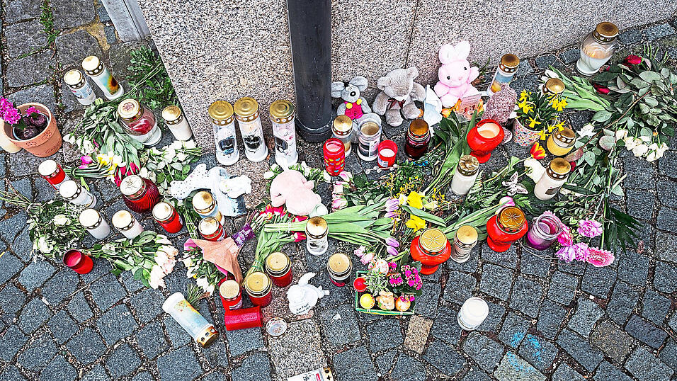 An der Stra&szlig;enecke zur Zufahrtsstra&szlig;e zum Kinder- und Jugendhilfezentrum, in dem eine Zehnj&auml;hrige tot aufgefunden wurde, liegen Blumen, Kuscheltiere und Grablichter auf dem Gehweg.