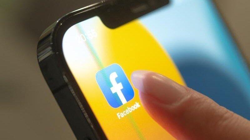 Eine Frau hält ihr Handy in der Hand, auf dem die Facebook-App zu sehen ist. Eine Frau hält ihr Handy in der Hand, auf dem die Facebook-App zu sehen ist.