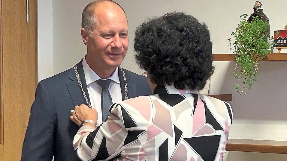 Die Amtskette wird B&uuml;rgermeister Thomas Etschmann von Liane Sedlmeier um den Hals gelegt.