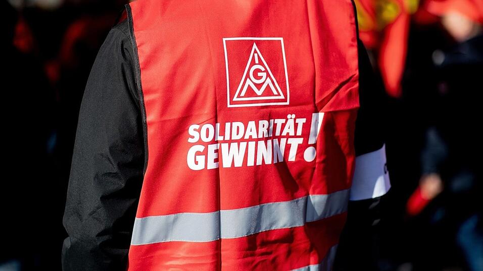 Ein Teilnehmer einer Kundgebung der IG Metall trägt eine rote Weste mit der Aufschrift 'Solidarität gewinnt!'. Ein Teilnehmer einer Kundgebung der IG Metall trägt eine rote Weste mit der Aufschrift 'Solidarität gewinnt!'.