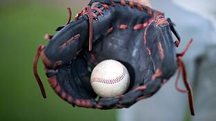 Ein Baseball liegt in einem Fanghandschuh.