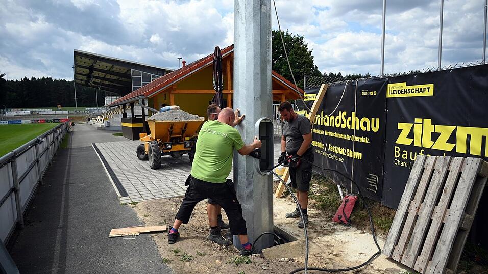 Bauleiter Martin Valentin und seine Mitstreiter Florian Wolf und Florian Demel stellen den Flutlichtmasten im Manfred-Zollner-Stadion in Vilzing auf.