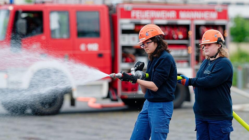 Ilias (links) und Annabella, Mitglieder der Jugendfeuerwehr in Mannheim, halten bei einer Übung einen Feuerwehrschlauch in den Händen. Ilias (links) und Annabella, Mitglieder der Jugendfeuerwehr in Mannheim, halten bei einer Übung einen Feuerwehrschlauch in den Händen.