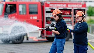 Ilias (links) und Annabella, Mitglieder der Jugendfeuerwehr in Mannheim, halten bei einer &Uuml;bung einen Feuerwehrschlauch in den H&auml;nden.