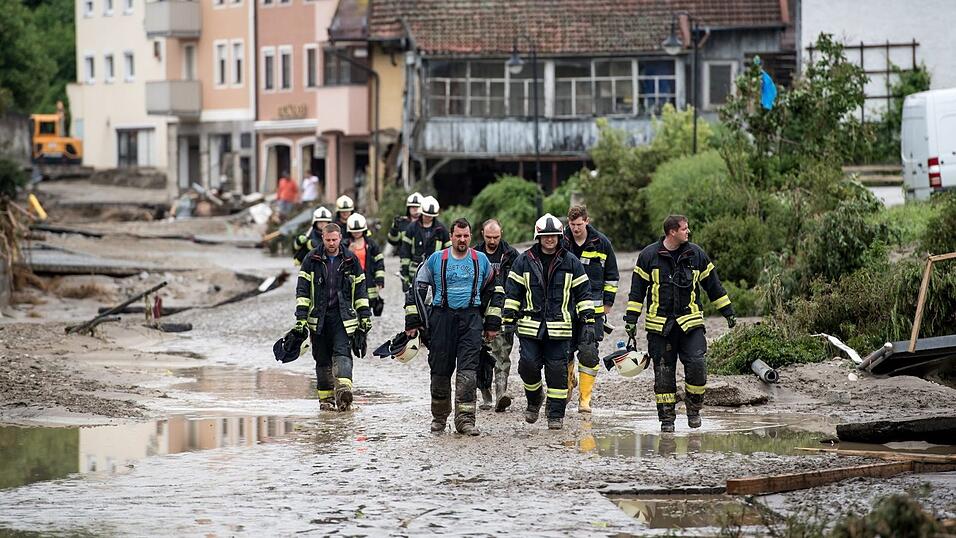 Feuerwehrleute gehen am 2. Juni 2016 durch die verw&uuml;steten Stra&szlig;en in Simbach am Inn.