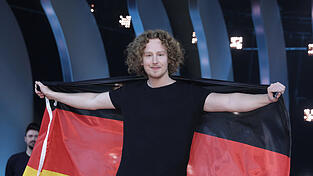 Eingeh&uuml;llt in die Deutschlandfahne freut sich S&auml;nger Michael Schulte &uuml;ber den Sieg. Er soll Deutschland mit dem Song 'You Let Me Walk Alone' beim ESC-Finale am 12. Mai in Lissabon vertreten.