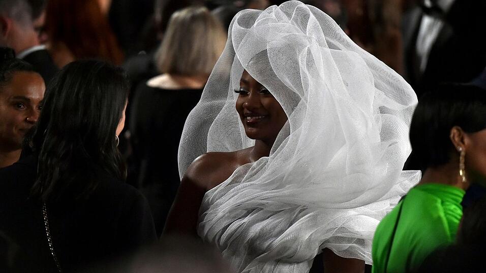 Sie f&auml;llt auf: S&auml;ngerin Tems kommt in einem aufregenden wei&szlig;en Outfit zur Oscar-Verleihung. Weniger Gl&uuml;ck hatten allerdings die G&auml;ste, die im Saal hinter ihr sa&szlig;en.