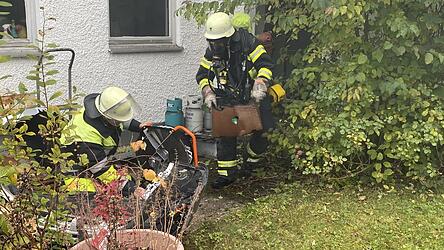 Atemschutztrupps befördern Brandgut aus dem Gebäude, während ein Drucklüfter vorbereitet wird.