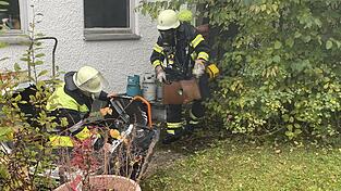 Atemschutztrupps befördern Brandgut aus dem Gebäude, während ein Drucklüfter vorbereitet wird.