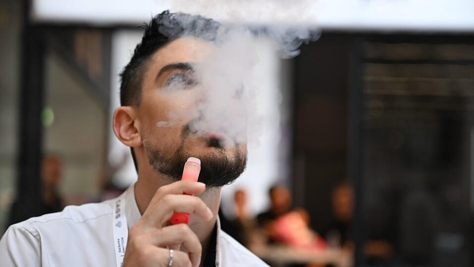 Ein Verk&auml;ufer einer E-Zigaretten-Firma nutzt bei der Dortmunder Messe Intertabac demonstrativ eine E-Zigarette. Der Verkauf dieser Produkte boomt. (Archivbild)