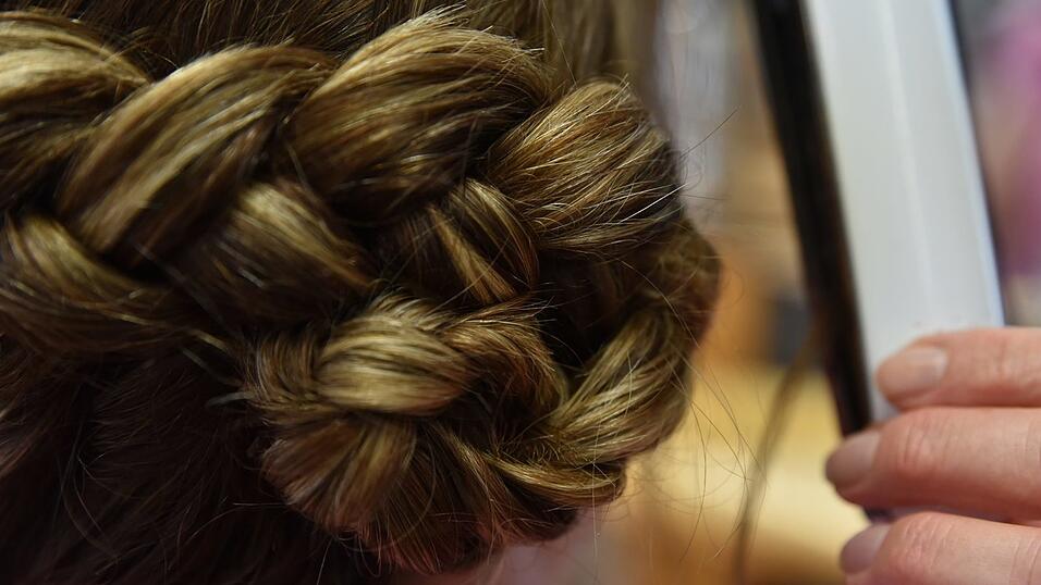 Der Zopf wird nun zu einem Dutt zusammengerollt und mit Haarklammern fixiert. Der Zopf wird nun zu einem Dutt zusammengerollt und mit Haarklammern fixiert.