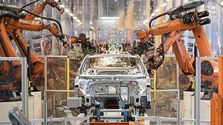 Teile eines VW Passat werden im Karosseriewerk von VW von Kuka-Robotern zusammengefügt. Der Augsburger Roboterhersteller plant den Abbau von 400 Stellen am Unternehmenssitz, insbesondere weil die Nachfrage aus der Autobranche schwach ist. (Archivbild)