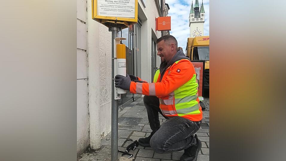 Roman Pflaumer von der SER bei der Montage eines neuen Aschenbechers am Ludwigsplatz beim Jakobsbrunnen.