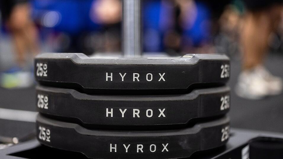 Hantelscheiben mit dem Schriftzug Hyrox an einem Messestand, wo wenig sp&auml;ter ein Lauf- und Workout-Wettbewerb stattfinden sollte.