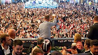 Bundeskanzler Friedrich Merz (CDU) prostet bei seinem Besuch des Oktoberfests Bierzeltbesuchern von der Empore in der Festhalle Schottenhamel zu.