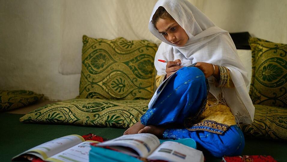 Die zehnj&auml;hrige Hajira aus der afghanischen Provinz Nangarhar sitzt in einem Haus in einem abgelegenen Dorf &ouml;stlich von Kabul &uuml;ber Schulb&uuml;chern und lernt.